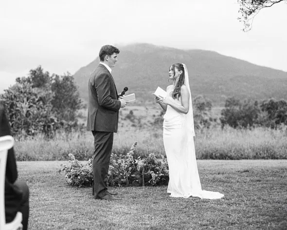 Alex and Will facing each other during their vow exchange, black and white