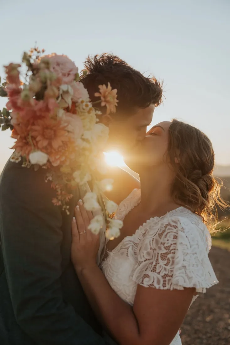 Nicola and Aaron kissing at sunset with florals at Maroon Hill Estate