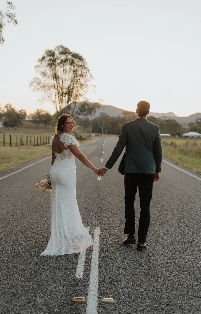 Nicola and Aaron walking away hand in hand down a country road at dusk
