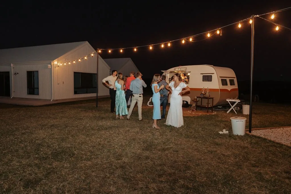 Wedding guests dancing under festoon lights beside the reception marquee at night