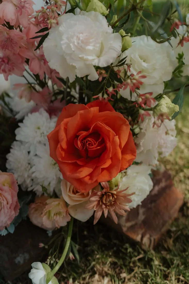 Close-up of the bridal bouquet with an orange rose, white blooms and pink florals
