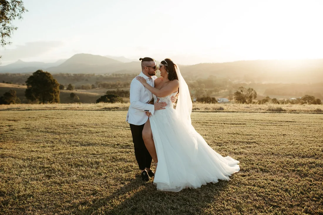 Groom nuzzling the bride's cheek in a golden field at Maroon Hill Estate