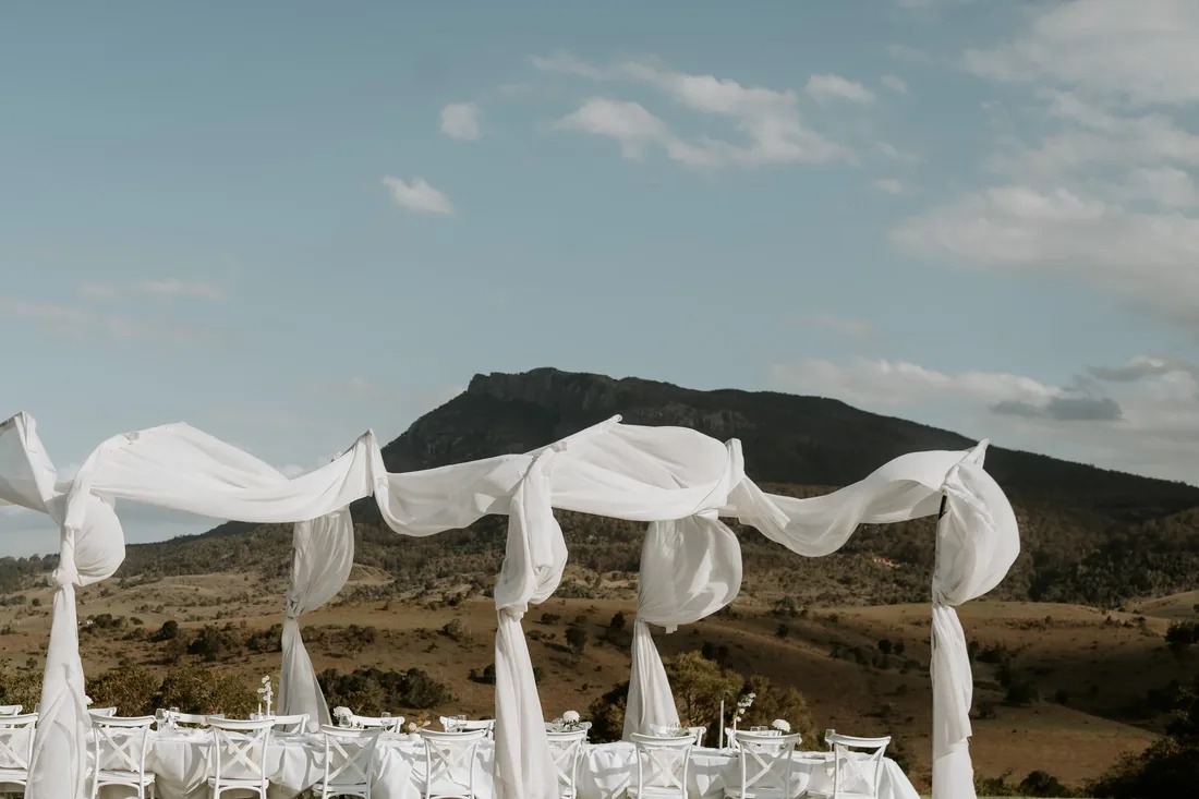 Row of sheer white drapery installations framing empty ceremony seating with a mountain backdrop