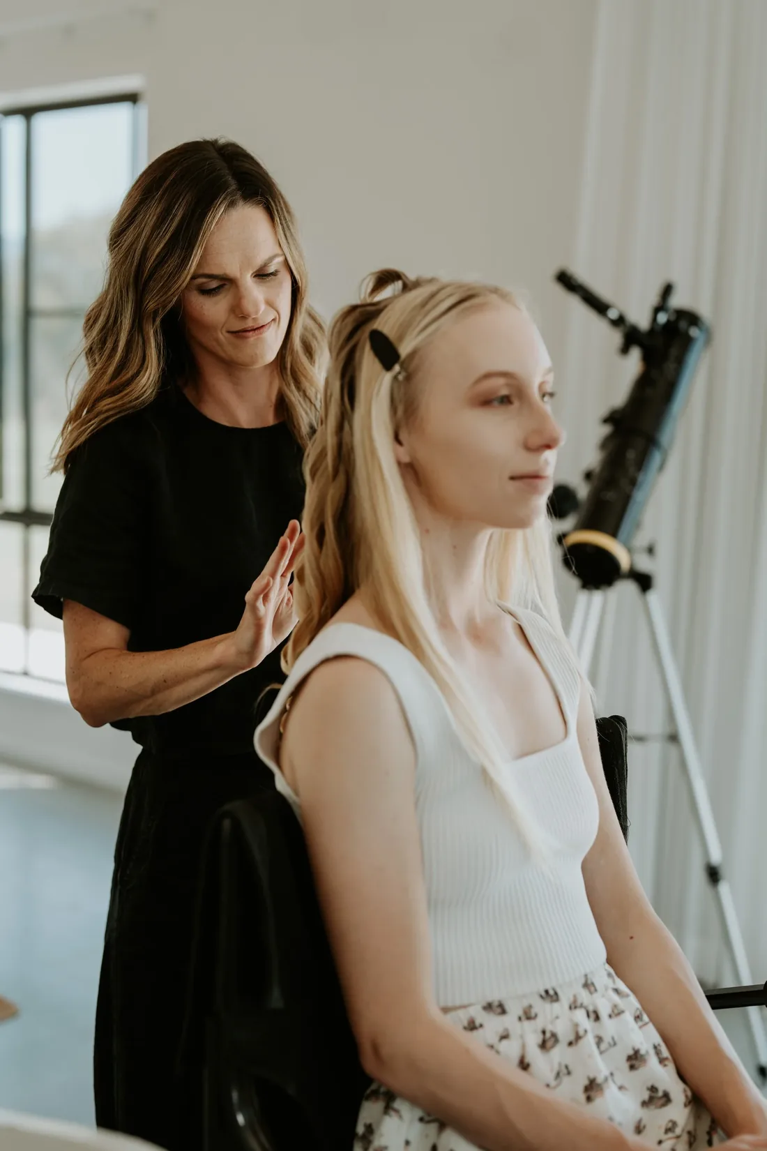 Hairstylist finishing the bride's half-up style backstage before the shoot
