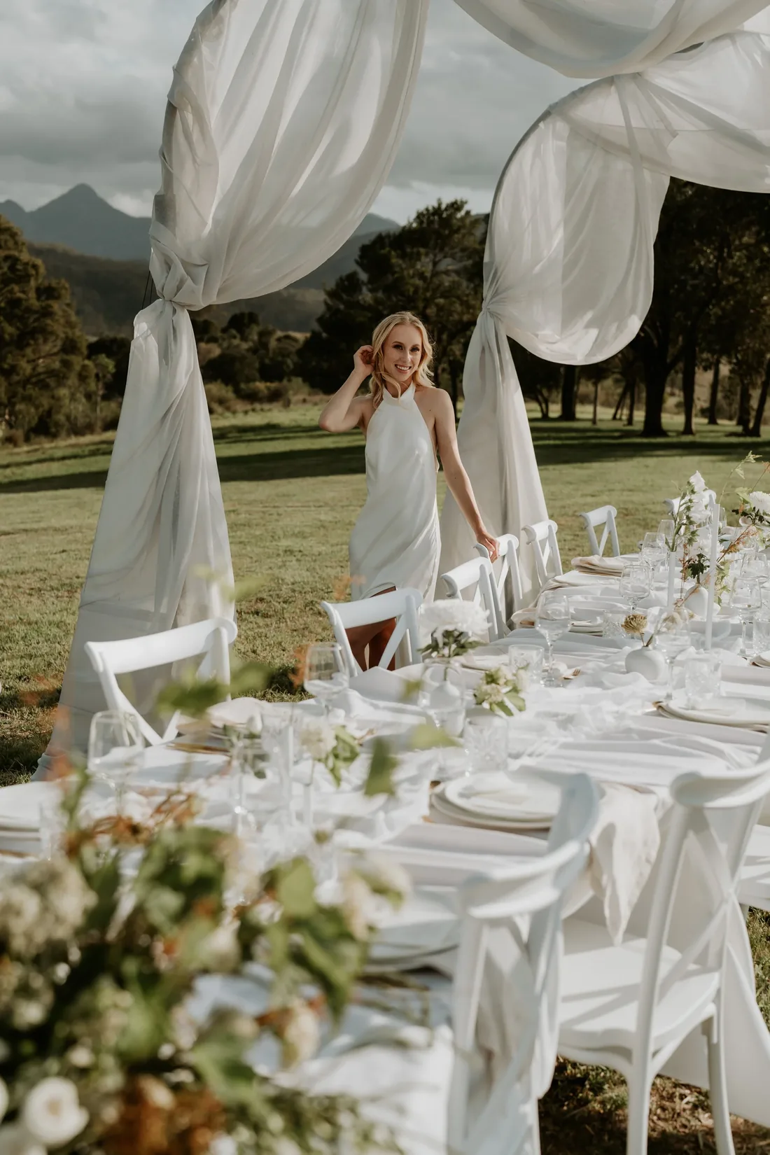 Table setting beneath a sheer fabric canopy with candlelight and the mountain silhouette at dusk
