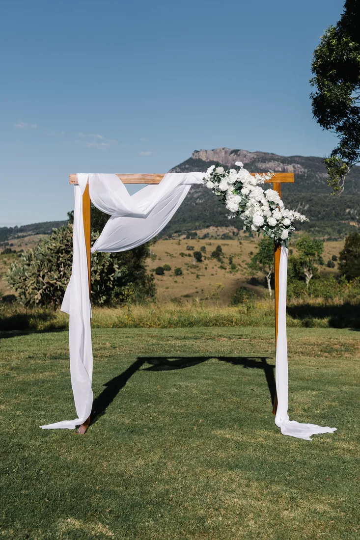 White ceremony arch with floral detailing overlooking the mountains at Maroon Hill Estate
