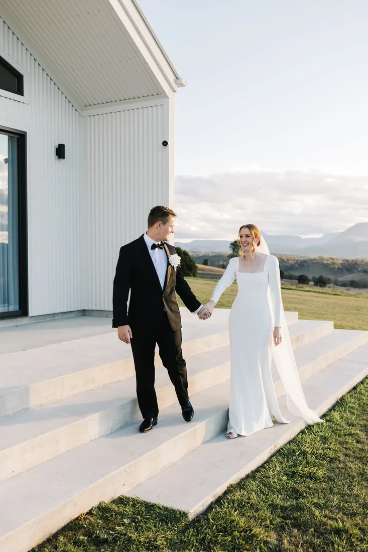 Sally and Joshua walking down the venue steps at Maroon Hill Estate, holding hands