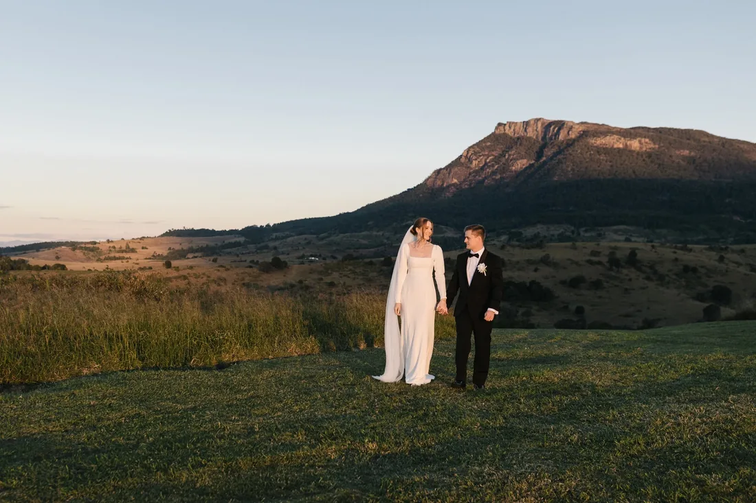 Sally and Joshua standing together with Mount Maroon rising behind them at dusk